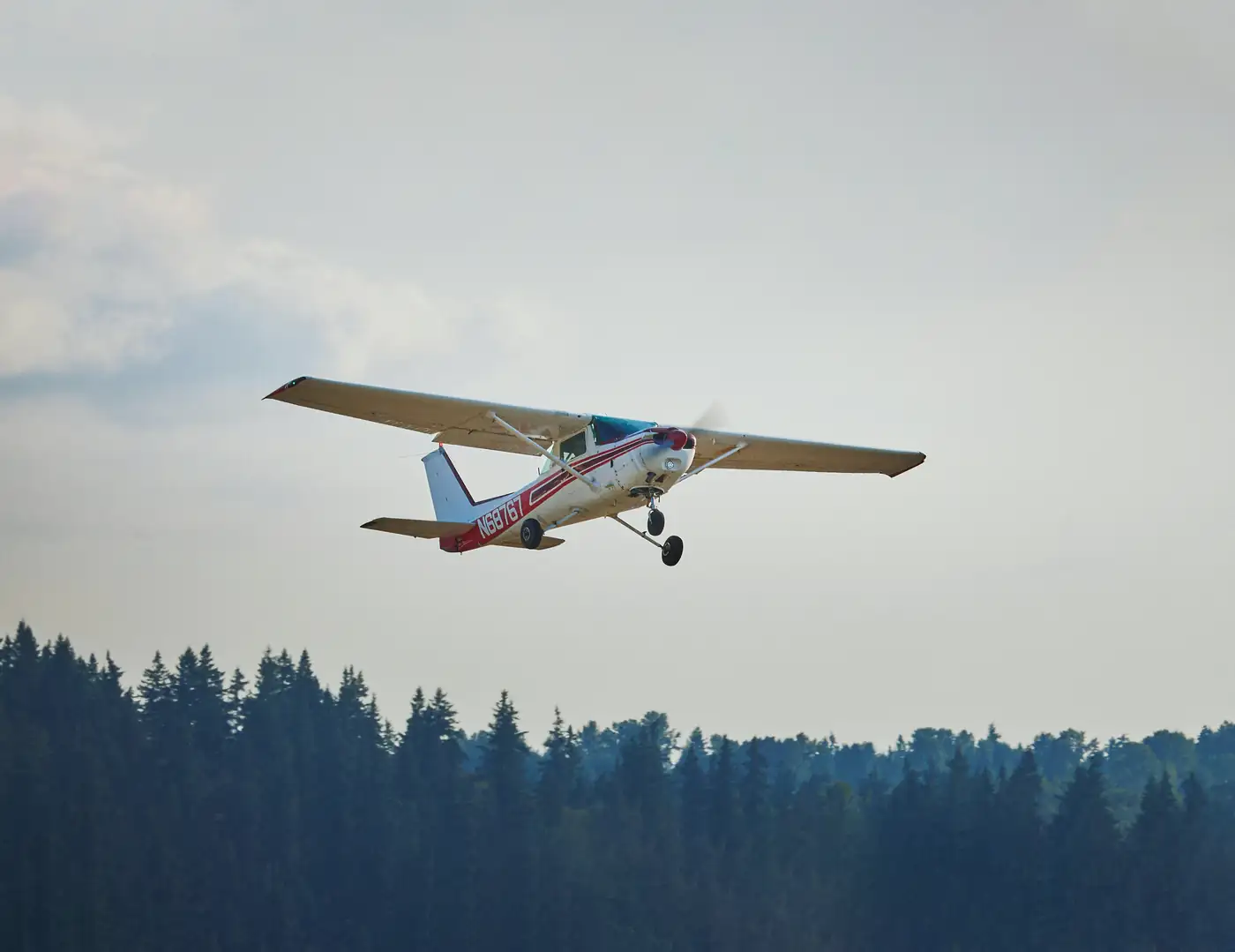 Cessna climbing out over trees