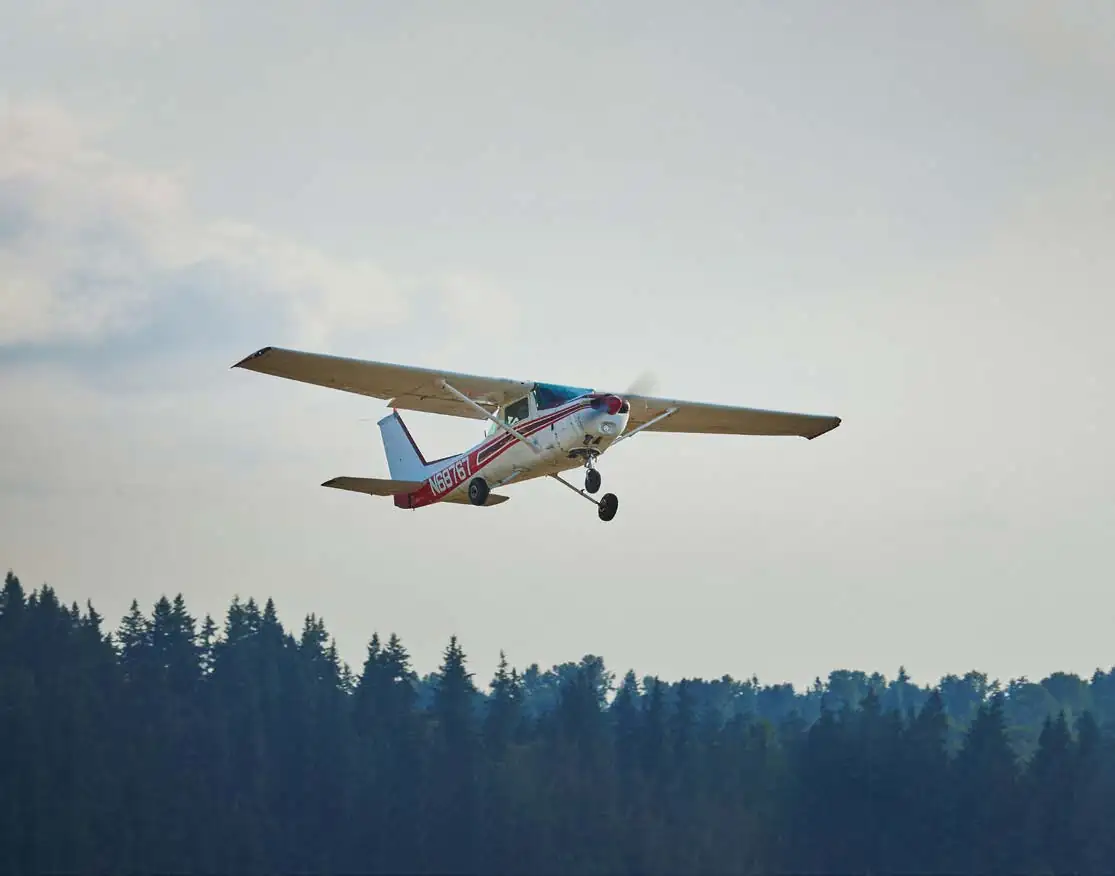 Cessna in flight over trees